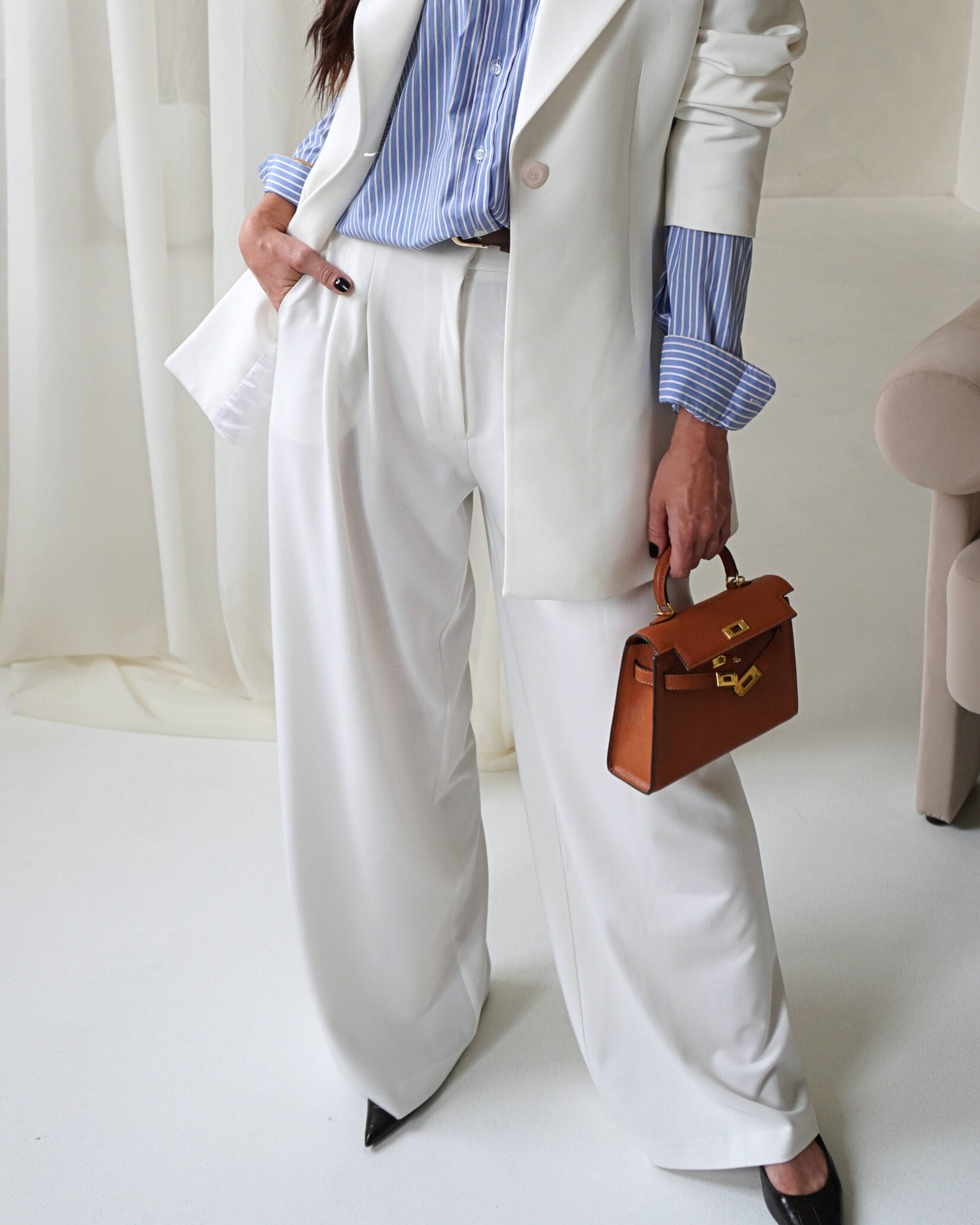 Model wearing THÉFI Dione high-waist wide-leg trousers in cream.