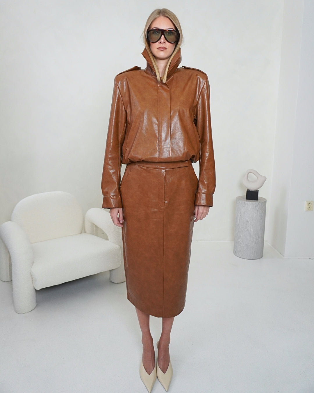 Full-length front view of the brown HERA Faux Leather Jacket styled with the matching THALIA Pencil Skirt by THÉFI.