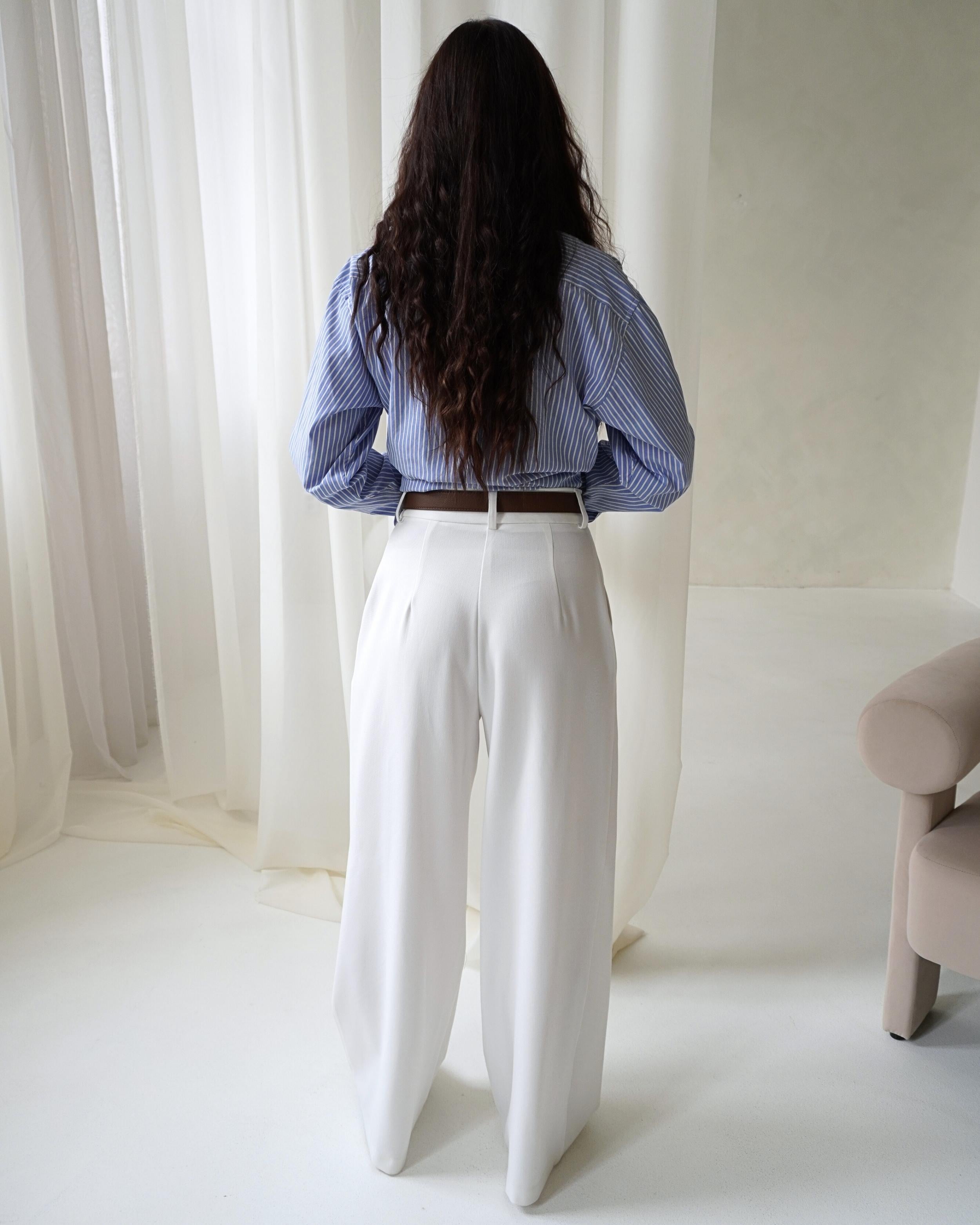 Model wearing THÉFI Dione high-waist wide-leg trousers in cream.