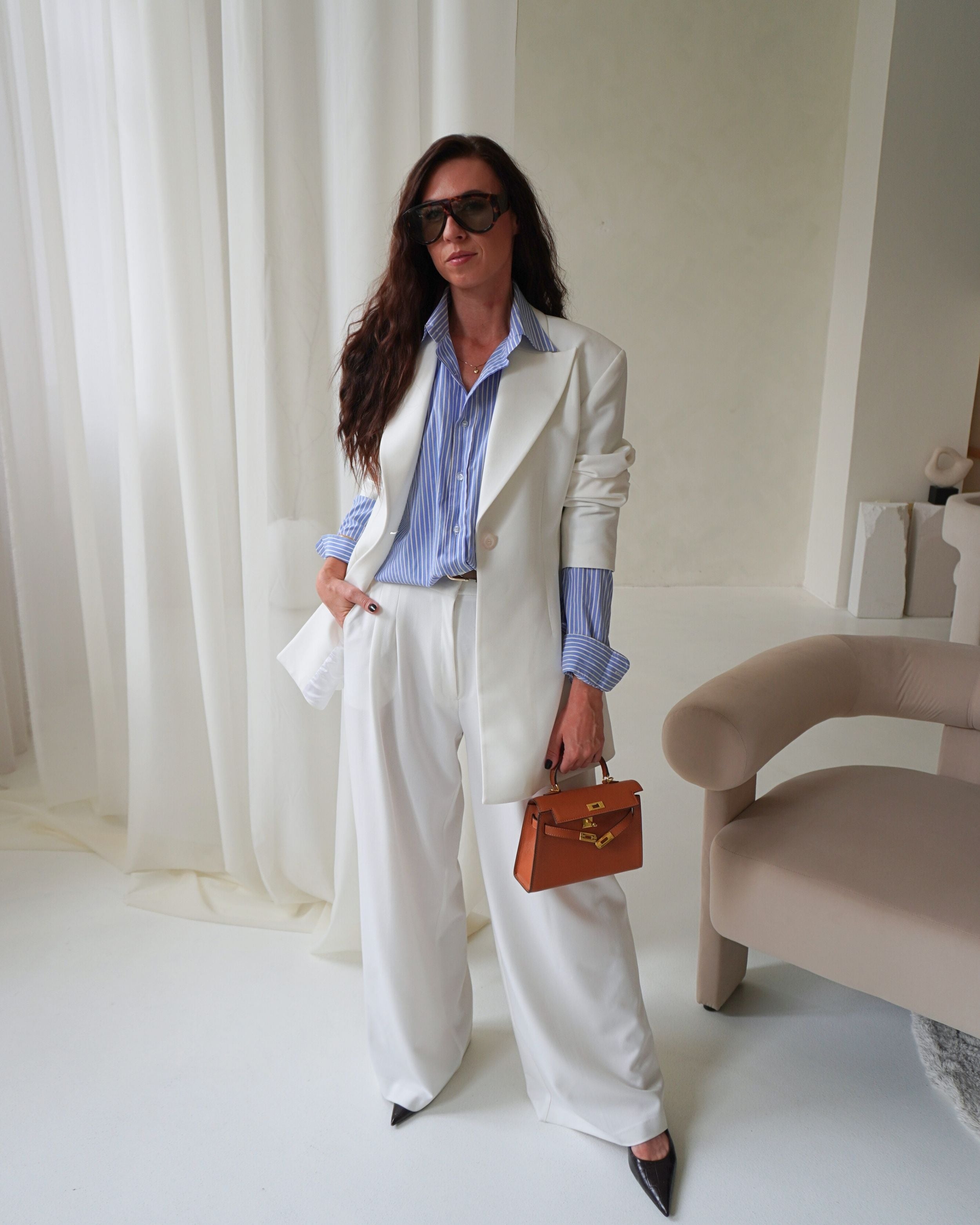 Model wearing THÉFI Dione high-waist wide-leg trousers in cream.