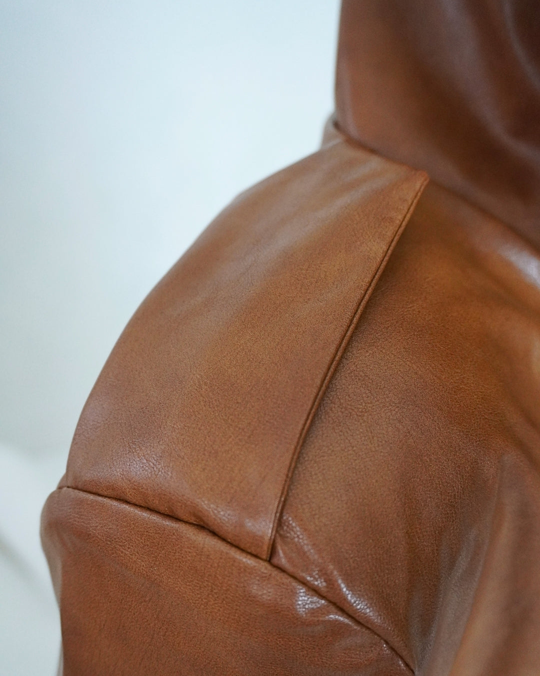 Close-up of the brown HERA Faux Leather Jacket showing the structured shoulder construction, stitching and faux leather texture.