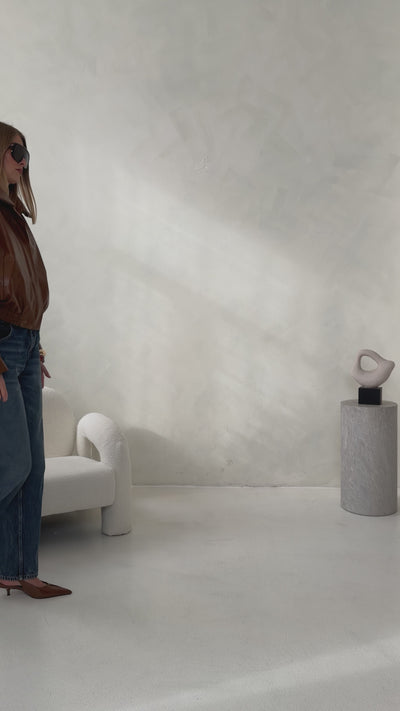 Video showcasing the brown HERA Faux Leather Jacket by THÉFI, highlighting its oversized silhouette, structured shoulders, statement funnel neck and gathered hem.